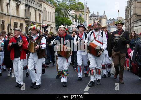 Oxford, UK. 1st May, 2017. A troop of Morris men lead the crowds celebrating May morning down the High Street from Magdalen Bridge. Crowds celebrate May morning in Oxford by watching the Morris men dance in front of Hertford College's Bridge of Sighs with the sun rising behind the bridge. May morning is traditionally celebrated in Oxford with a choir singing from the top of Magdalen College Tower after which the crowds are lead through the streets by Morris men who perform at various sites throughout the city. Credit: Jill Walker/Alamy Live News Stock Photo