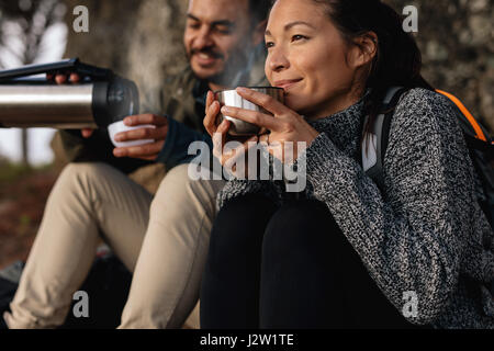 Young couple taking a break on a hike. Man and woman drinking coffee while out hiking. Stock Photo