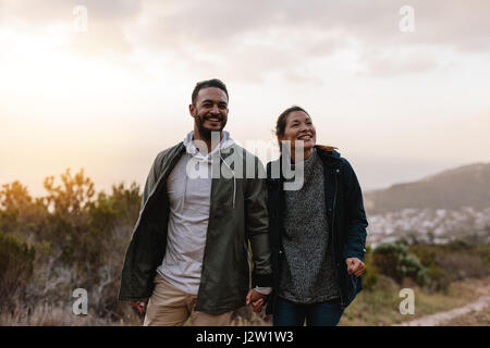 Portrait of couple of happy hikers walking in the countryside. Young man and woman hiking and looking away. Stock Photo