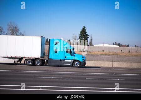 Bright blue modern road train of the semi truck and the dry van trailer streamlined aerodynamic skirt on the highway with lots of traffic lanes separa Stock Photo