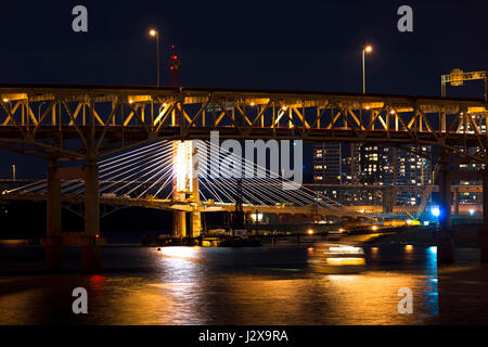 Modern rope and classic truss bridges across the evening Willamette river in downtown Portland in a blaze of illumination lights and reflection Stock Photo
