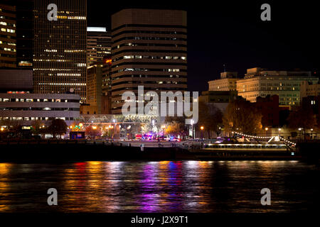 Walking and excursion boat at the pier on the waterfront in the center of the night Portland on Willamette River surrounded by shining and reflected Stock Photo