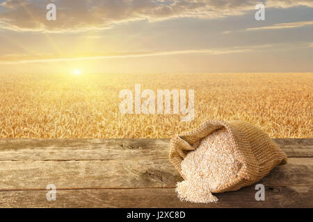 bran in sack on table with ripe cereal field on the background. Food supplement to improve digestion. Dietary fiber. Product for healthy nutrition and Stock Photo