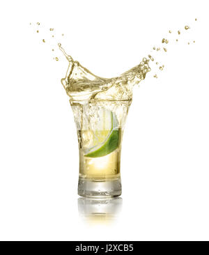 gold tequila shot with lime slice and splash isolated on white background. Lime is falling in the alcohol drink. Splash of tequila from the falling pi Stock Photo