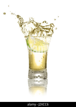 gold tequila shot with lime slice and splash isolated on white background. Lime is falling in the alcohol drink. Splash of tequila from the falling pi Stock Photo