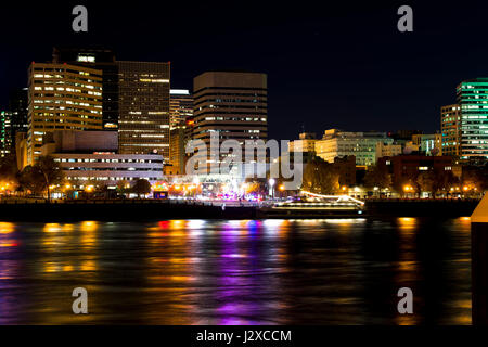 Elegant evening boat trip on the river in a posh Portland buildings with the shining lights, walking around people, colorful reflection Stock Photo