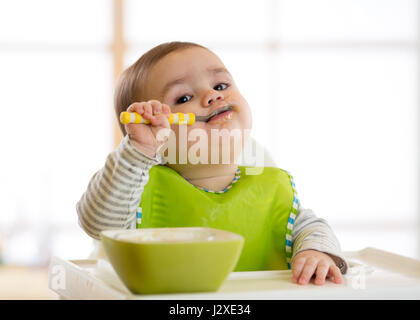 Happy baby boy spoon eats itself Stock Photo