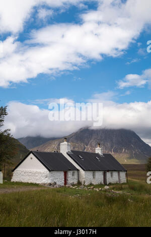 Stunning view of Black Rock Cottage in the Scottish highlands, with a view of Buachaille Etive Mòr on a sunny day, with clouds over the mountain. Stock Photo