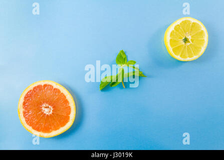 Top view of grapefruit and lemon slices and mint leaves on blue background. Minimalist picture style with copy space for text Stock Photo