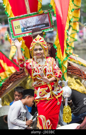 Unidentified young girl perform Traditional dance inside the  Bajau's boat called Lepa-Lepa decorated with colorfull Sambulayang flag during Regatta. Stock Photo