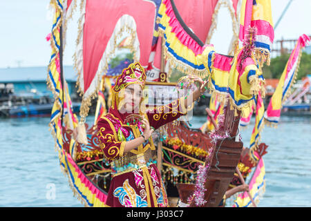 Unidentified young girl perform Traditional dance inside the  Bajau's boat called Lepa-Lepa decorated with colorfull Sambulayang flag during Regatta. Stock Photo