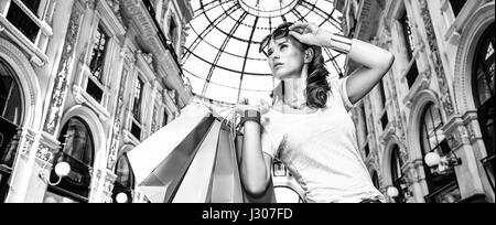 Discover most unexpected trends in Milan. Fashion monger with eyeglasses and colorful shopping bags in Galleria Vittorio Emanuele II looking into the  Stock Photo