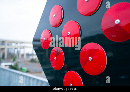Black square with fixed on it round red reflectors folded up the ranks as a road sign directing information and warning to drivers of vehicles Stock Photo