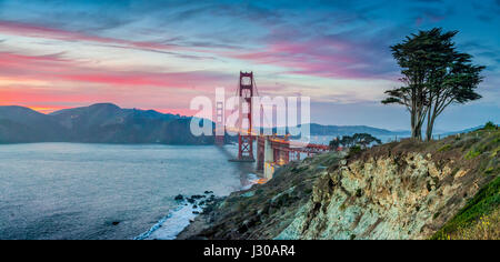 Classic panorama view of famous Golden Gate Bridge seen from scenic Baker Beach in beautiful post sunset twilight with blue sky and clouds at dusk Stock Photo