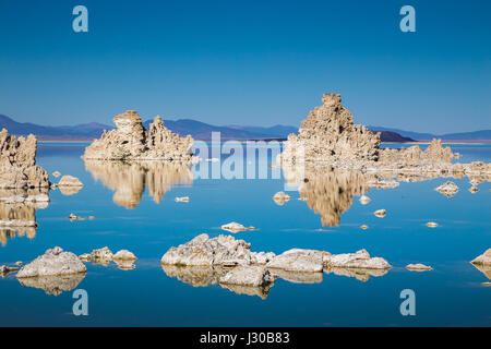 Classic view of fascinating tufa rock formations mirrored on calm water surface of famous Mono Lake on a beautiful sunny day with blue sky in summer Stock Photo
