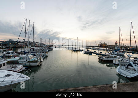 England, Ramsgate harbour. Dawn sky with sun breaking out from cloud layer. Yachts and boats moored in the out harbour marina. Stock Photo