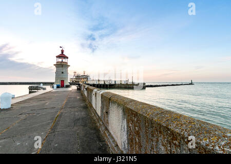 England, Ramsgate harbour. Dawn sky with lighthouse at end of harbour jetty, and in the background, the harbour offices on other harbour jetty. Sky with cloud layer, sunrise hidden. Stock Photo
