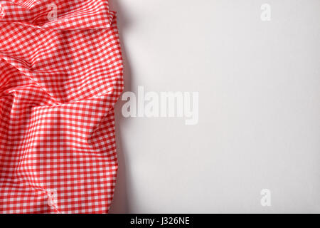 Red and white checkered fabric on white table. Top view. Horizontal composition. Stock Photo