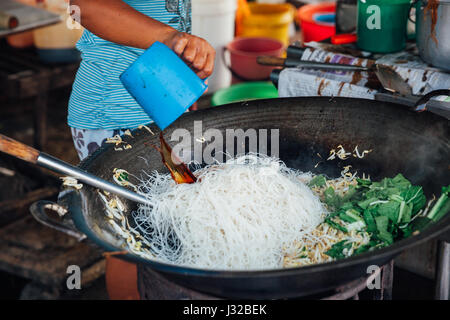 GEORGE TOWN, MALAYSIA - MARCH 23: Woman cooks stir-fried noodles with bean sprouts at Kimberly Street Food Night Market on March 23, 2016 in George To Stock Photo