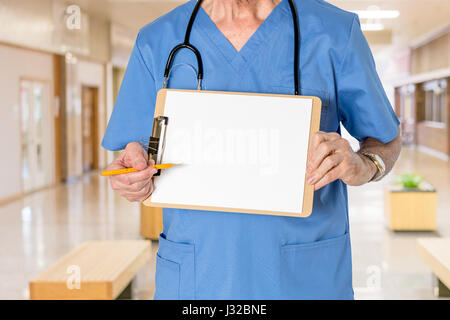 Doctor with stethoscope in medical scrubs holding blank clipboard for healthcare message Stock Photo