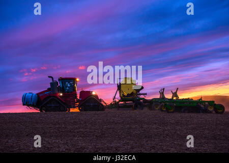 Case quadtrac tractor with fertilizer tanks pulling an air drill planting spring wheat at sunset in the Palouse region of Washington Stock Photo