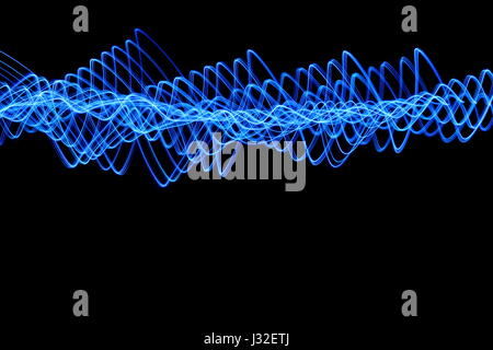 Long exposure photograph of neon blue colour in an abstract wavy pattern against a black background. Light painting photography, abstract colour Stock Photo