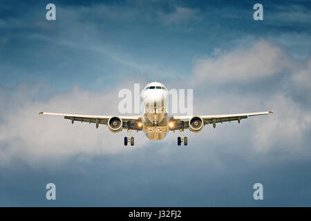 Front view of a big jet plane taking off on blue cloudy sky background Stock Photo