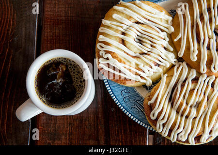 Overhead view of a cup of coffee and cinnamon rolls on a rustic wood table Stock Photo