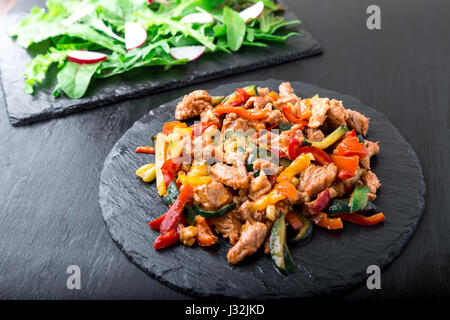 Fry meat with vegetables near salad with arugula and radish on stone slate plates. Dinner.  Delicious healthy lunch Stock Photo