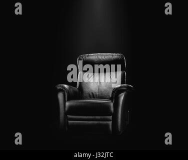 Black leather armchair in spotlight, dark background Stock Photo