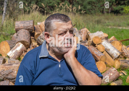 Portrait of elderly Ukrainian peasant ready to chop firewood for house heating in winter Stock Photo