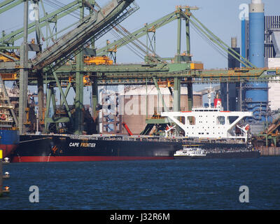 The 'Cape Frontier' is a bulk carrier ship, built in 2006 and registered with IMO number 9364320. It is pictured docking at Mississippihaven in the Port of Rotterdam, one of the largest ports in Europe. The image captures the ship's large-scale design and its role in international trade and transportation. Stock Photo