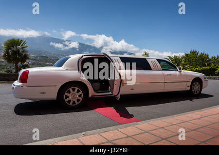 White Lincoln limousine car decorated for a wedding party and with red carpet leading to open door. Stock Photo