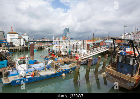 The busy Camber docks in Portsmouth Hampshire. Assortment of fishing boats old and new with local landmarks in the background. Stock Photo