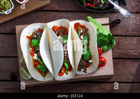 mexican steak and chicken fajitas in cast iron skillet shot top down with corn tortillas Stock Photo