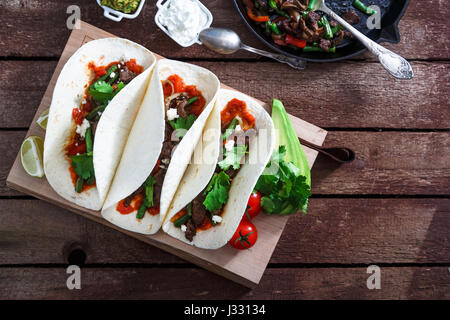 mexican steak and chicken fajitas in cast iron skillet shot top down with corn tortillas Stock Photo