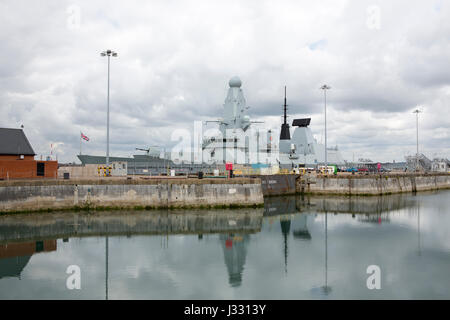 Type 45 Destroyer of the Royal Navy alongside in HMNB Portsmouth. Taken from inside the dockyard showing reflection in a still basin. Stock Photo