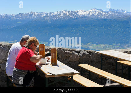 A couple sitting on wooden benches and eating outside the Hefelekar restaurant, Tirol, Austria Stock Photo