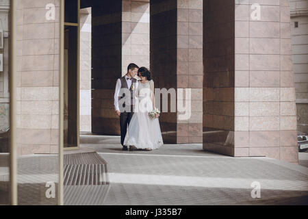 bride and groom stand near tall columns Stock Photo