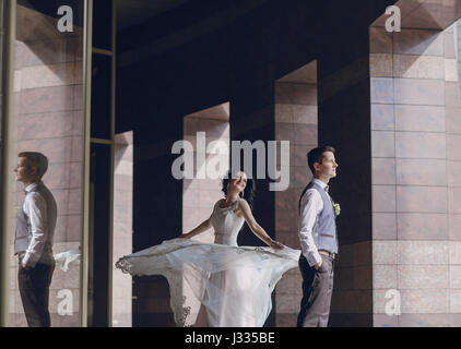 bride and groom stand near tall columns Stock Photo