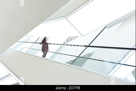 woman on an escalator in white simplistic interior of Openbare Bibliotheek, Amsterdam, Netherlands Stock Photo
