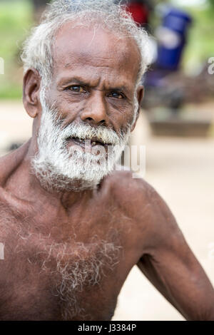 Illustrative image. Pondicherry, Tamil Nadu, India - April 14, 2014. Portrait of senior indian man in traditional costume. Poor men sad smiling sittin Stock Photo