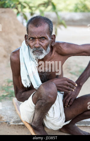 Illustrative image. Pondicherry, Tamil Nadu, India - April 14, 2014. Portrait of senior indian man in traditional costume. Poor men sad smiling sittin Stock Photo