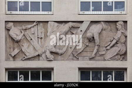 Accident on construction works. Relief by Hungarian sculptor Janos Zsakodi Csiszer (1930) on the north wing of the Art Deco building of the Budapest Workers Insurance Fund in Budapest, Hungary. The building, now used as the seat of the National Social Insurance Centre (OTI), was designed by Hungarian architects Marcell Komor and Dezso Jakab and built in 1913. The north wing was added by architect Aladar Sos in 1930-1931. Stock Photo