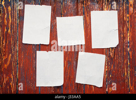 Blank torn scraps of paper on red wooden wall Stock Photo