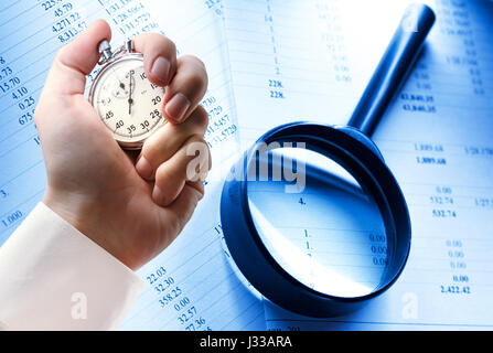 Budget papers, magnifying glass and stopwatch in male hand Stock Photo