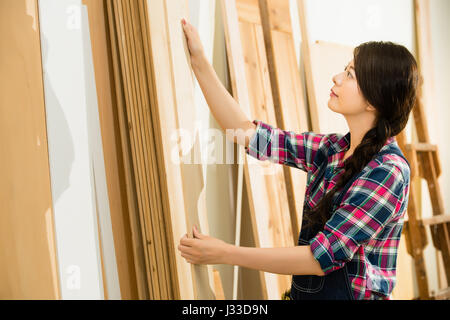 carpenter testing wood plank evenness and choosing best wood board at workshop. mixed race asian chinese model. Stock Photo