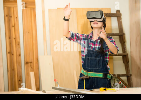 Man doing woodwork in carpentry. Carpenter work on wood plank with vr headset device in workshop. mixed race asian chinese model. Stock Photo