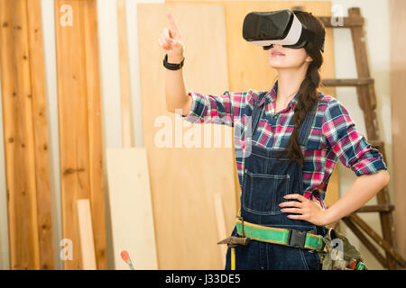Artisan woodworker touch screen with in simulation virtual reality, carpenter standing and experience using a VR glasses device. mixed race asian chin Stock Photo