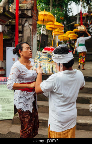 UBUD, INDONESIA - MARCH 2: Child helps his mother during the celebration before Nyepi (Balinese Day of Silence) on March 2, 2016 in Ubud, Indonesia. Stock Photo